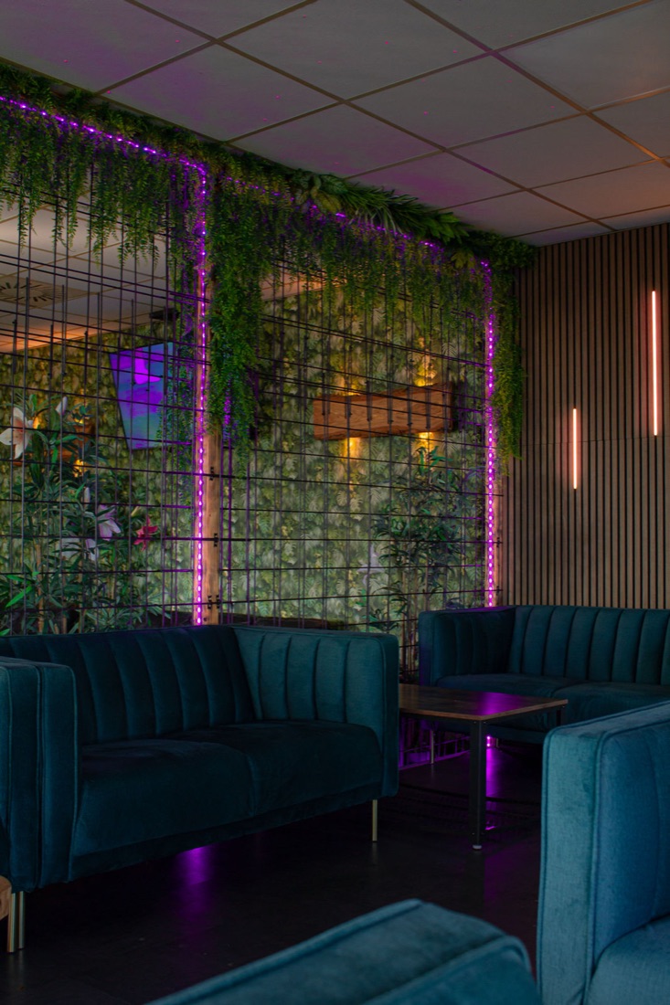 Lounge-Bereich mit begrünter Wand und Samtsofas